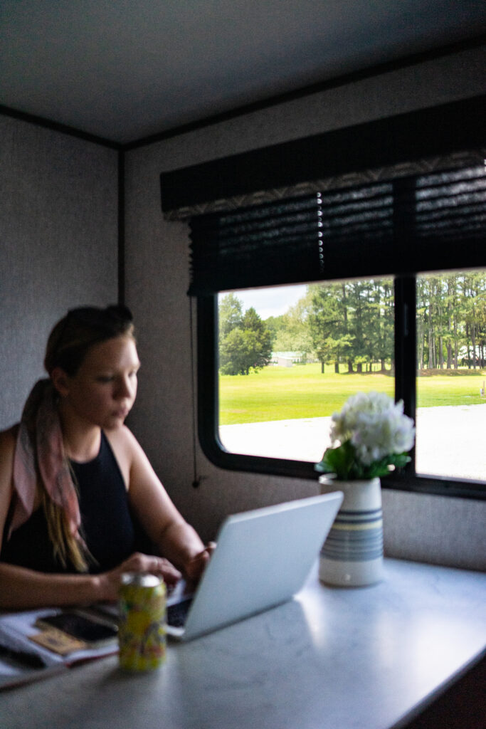 A woman working on a computer at an RV table