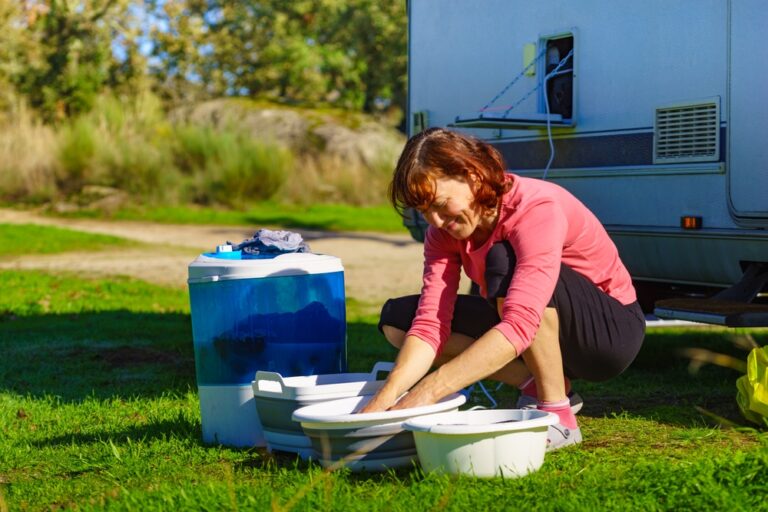 A woman next to an RV using a portable washing machine