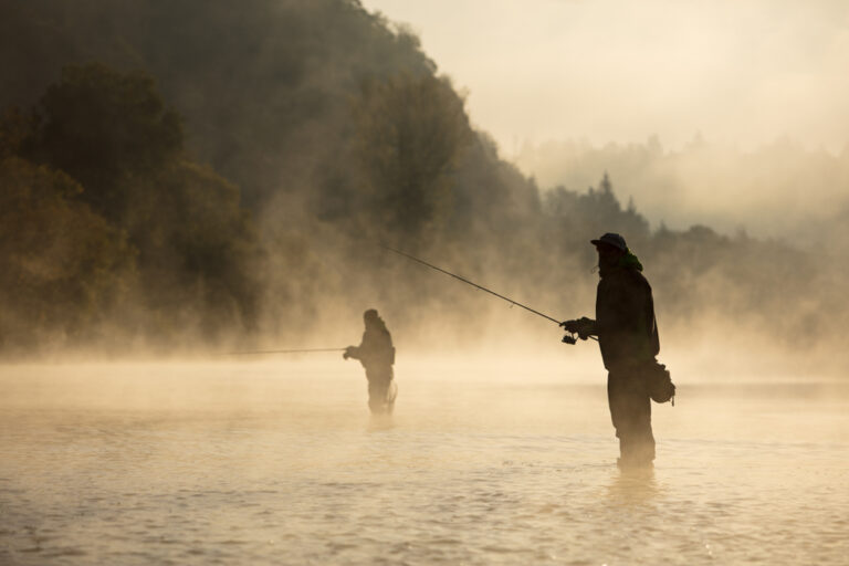 People fishing on a foggy lake