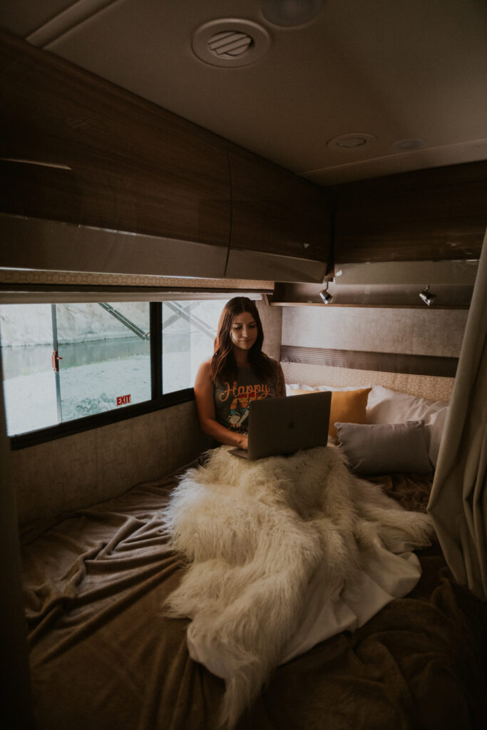 A woman working on a laptop on an RV bed