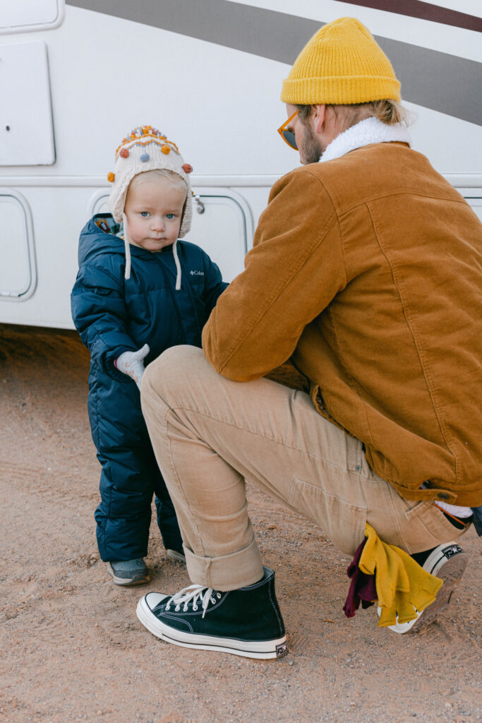A dad and kid in snow gear in front of an RV