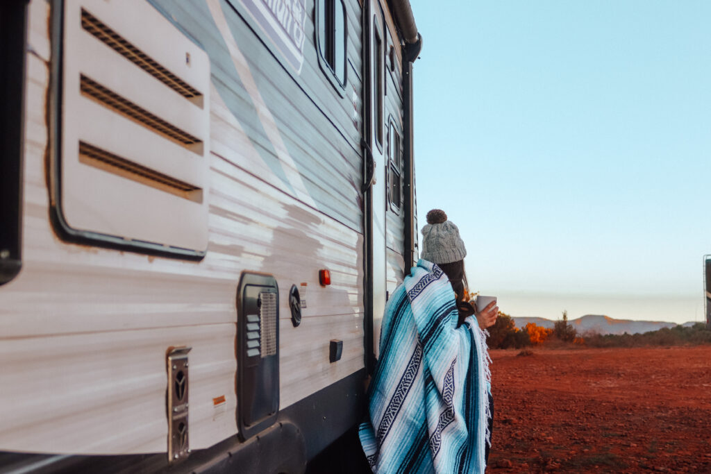 A woman wrapped in a blanket, standing next to an RV