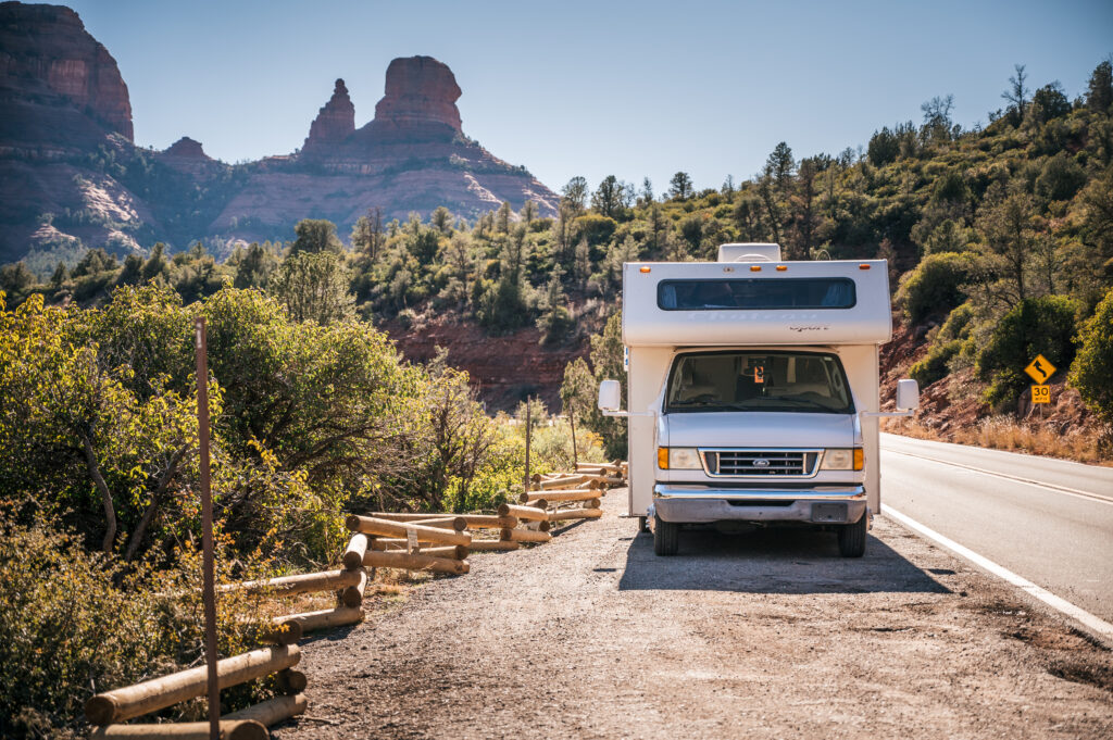A Class C RV parked in front of red rocks