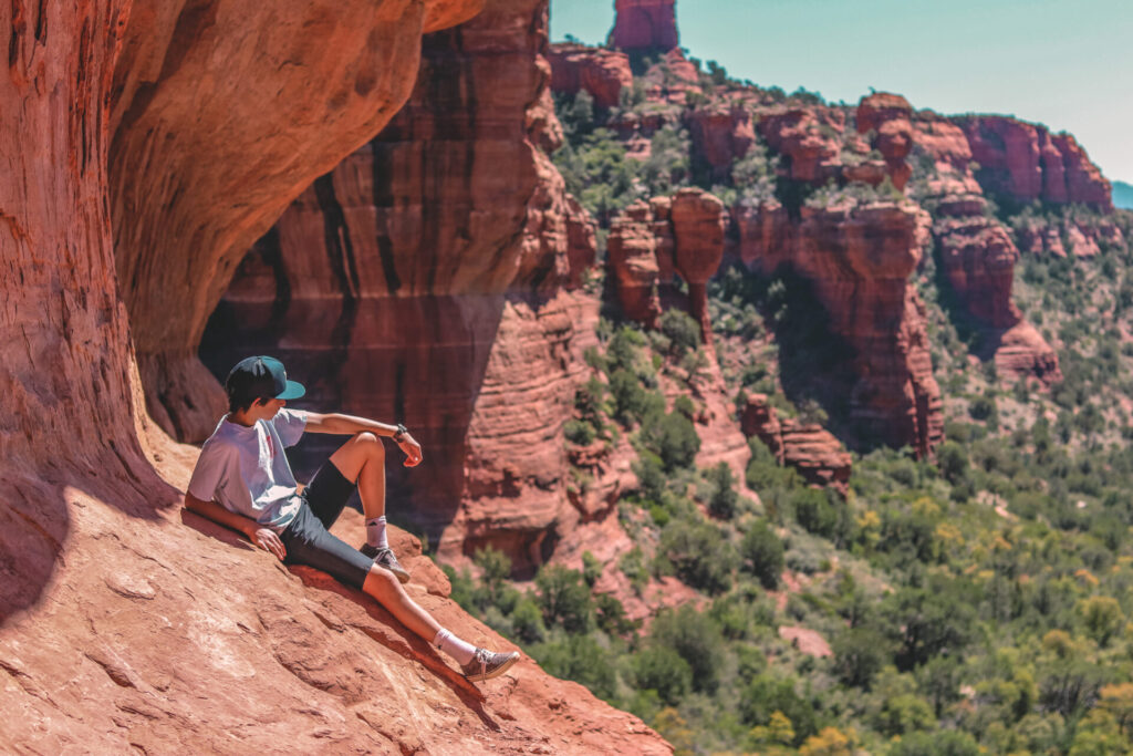 a kid relaxing on the side of a red rock