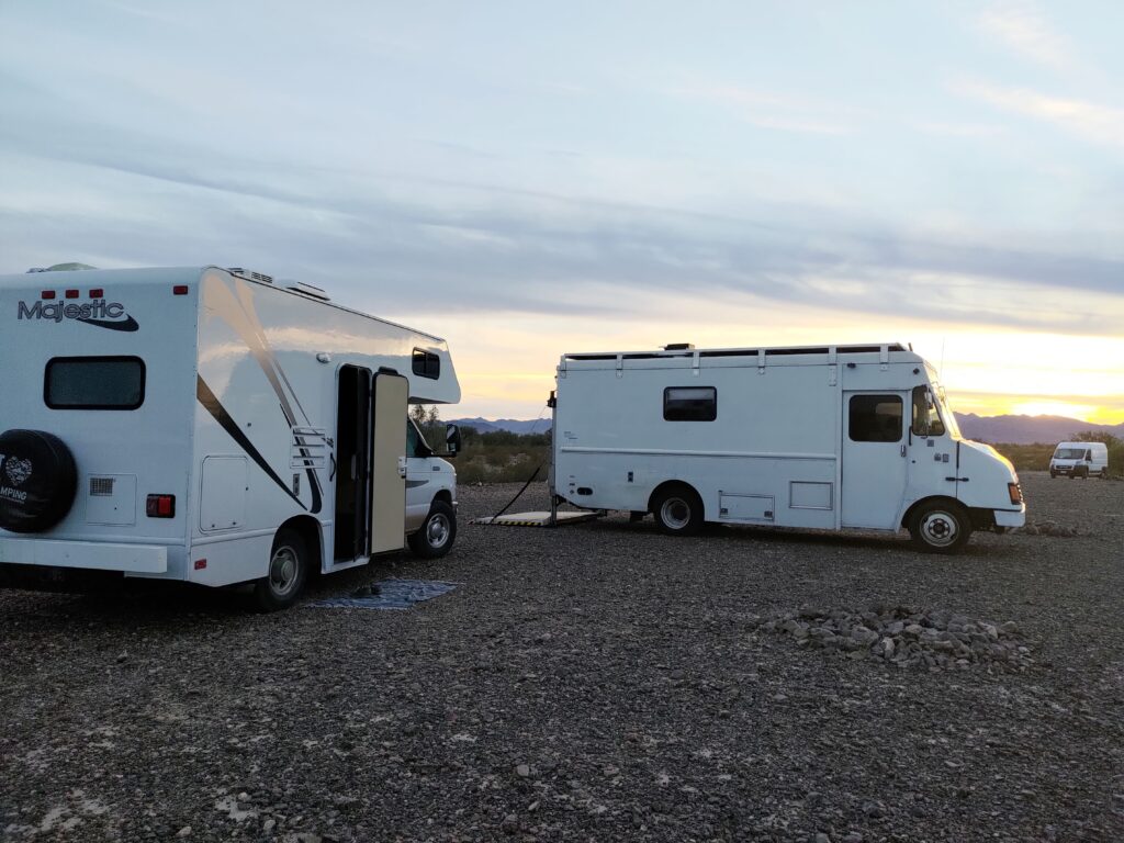 Two Class C RVs parked in an open landscape