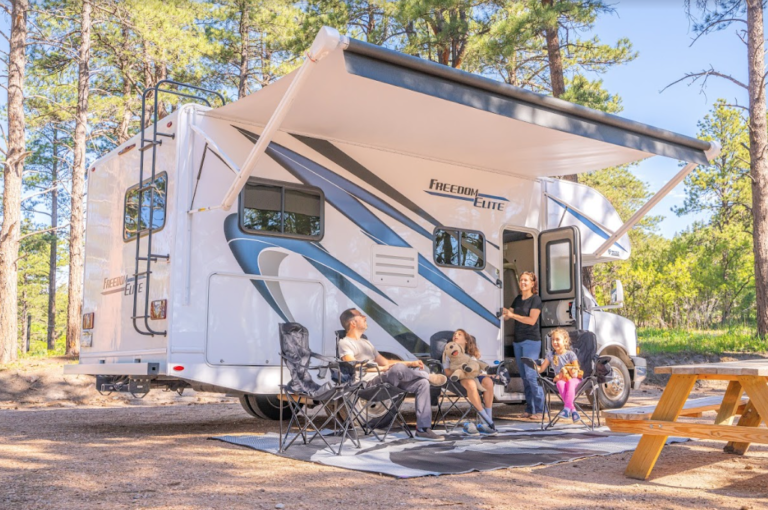 a family sitting outside their RV under an awning
