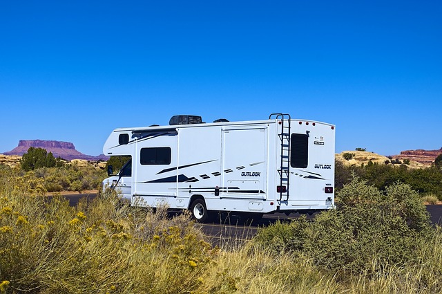 A Class C camper set up near Needles with a red rock butte in the background