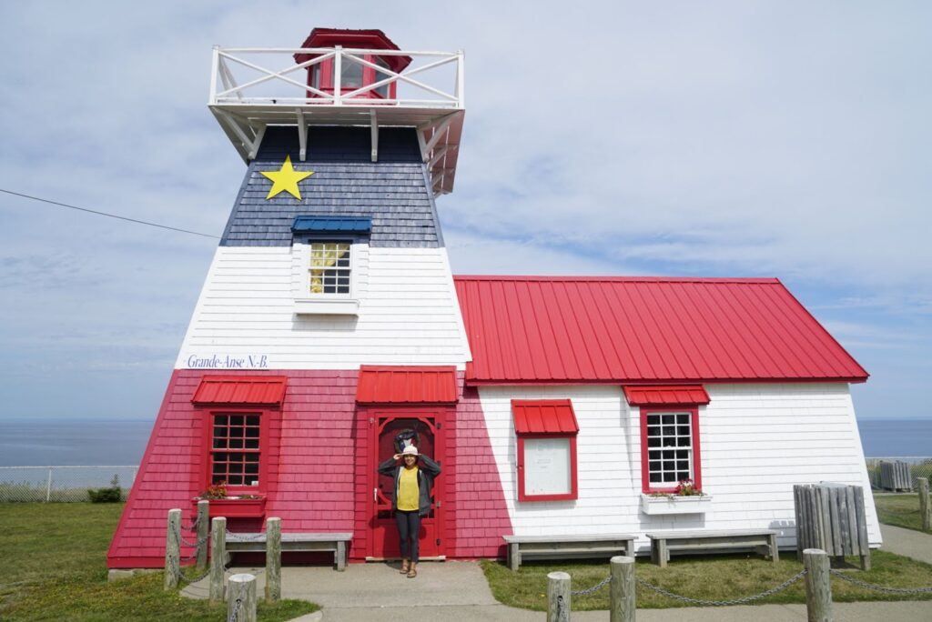 Woman stands in front of a lighthouse